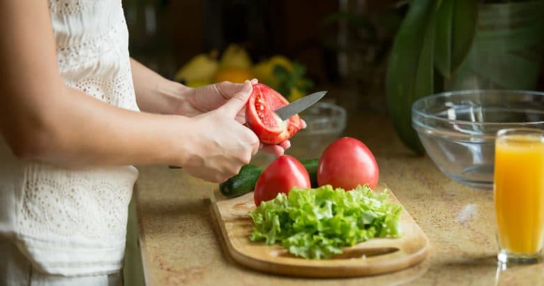 Dieta Vegana Gastando Pouco | Mãos cortando os tomates, salada no prato